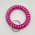 Close-up of a pink spiral telephone wire wristband with a silver metal key ring - Metallic Rose Red