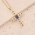 Detail der 18K Gold Kreuzkette mit tiefblauen Zirkonia auf natürlichem Steinhintergrund - Dunkelblau