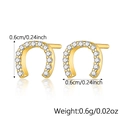 Macro view of gold horseshoe stud earrings with pavé set white zircon and size details - Horseshoe