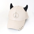 Close-up of beige baseball cap featuring black devil horns and metal ring decorations - Tower Beige