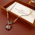 Close-up of ceramic heart pendant with clover metal detail and stone beaded chain - Heart Clover Style / Brown