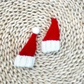 Dettaglio di due mini cappelli natalizi lavorati a maglia con pompon bianchi su stuoia - Cappello di Natale con Pompon 4*7CM