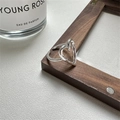 Silver open ring with hollow heart design on a dark wood frame next to perfume bottle - JZ0011 (Hollow Heart)