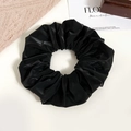 Detail of a large black satin scrunchie with pleated texture on minimalist background - Black