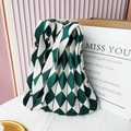 Detail view of a green and white checkered knit pleated shoulder bag on a white surface - Green & Beige Argyle