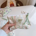 Close-up of floral cotton pouch with green leaves and pink stripes held by hand - Flesh Pink Striped Floral