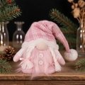 Primer plano de un gnomo navideño rosa de punto con trenzas sobre una mesa de madera - Gorro de cuadros rosa para mujer (con trenzas)
