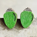 Detail of green light bulb Christmas earrings on a textured stone surface - Green Christmas Light