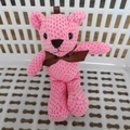 Detailed macro view of pink knit teddy bear plush featuring a brown ribbon bow detail - Rose Pink