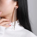 Detailed view of long multi-row rhinestone tassel earrings on a model with white knitwear - Silver Four-row Rhinestone Tassel