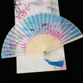 Close-up of Chinese folding fan with pink cherry blossoms and elegant blue tassel - Blue Eternal Love Peach Blossom