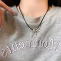 Gros plan d'un collier pendentif nœud argenté avec cordon noir sur un mannequin - Cordon Noir Pendentif Nœud