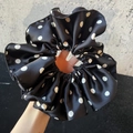 Elegante elastico per capelli in raso nero a pois bianchi mostrato in un primo piano nitido - Nero