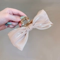 Close-up of champagne satin bow hair claw clip with a transparent grip and metal spring - Iridescent Bow Cream White
