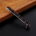 Dettaglio di cristalli di granato rosso scuro su un fermaglio in argento su sfondo nero - Granato con clip d'argento