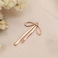 Detailed view of rose gold bow pendant accessory on elegant champagne satin fabric - Long Ribbon Bow (PJ0019) / Rose Gold