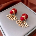 Detail showing 18K gold-plated double pearl earrings with red bead and metal charms - Letter DR Star Double Bead Earrings