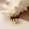 Detailed close-up of golden heart pendant with chocolate melt drip enamel effect on chain - Coffee