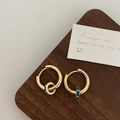 Close-up of golden hoop earrings with blue enamel charms on a dark wood display - Blue Single Hoop Earrings