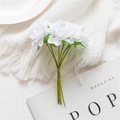 Artificial white silk flower bouquet tied with green stems on a white knitted texture - White