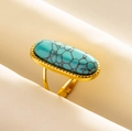 Detail eines Vintage-Türkisrings mit Gold-Finish in weichen cremefarbenen Stofffalten - Gold-Hellblau Türkis