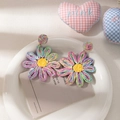 Close-up of woven raffia flower earrings with colorful petals and golden metallic links - Colorful