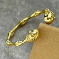 Primer plano del cráneo dorado en una pulsera punk de acero inoxidable sobre fondo rústico - Dorado
