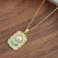 Détail macro du pendentif tournesol avec perle blanche et émail vert sur cadre doré - Collier Tournesol - Blanc