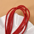Macro shot of 2x4mm smooth red turquoise cylindrical spacer beads on a ceramic plate - Red