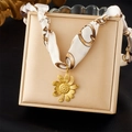 Dettaglio ciondolo girasole dorato su collana in nastro di seta su portagioie beige - Ciondolo Girasole Beige (N3606)