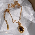 Détail du collier plaqué or 18k avec pendentif ovale en œil de tigre sur papier blanc - Collier Oeil de Tigre Ovale / Brun doré