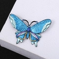 Macro shot of blue butterfly brooch with textured wings and sparkling blue rhinestones - Blue