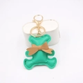 Close-up of green PU leather bear keychain with brown bow and gold metal ring - Green