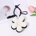 Close-up of black and white plush five-petal flower keychain with sturdy black clasp - Black & White