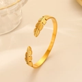 Detailed view of the gold feather-shaped open cuff bracelet in stainless steel - Gold Feather
