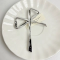 Dettaglio di una spilla a fiocco in metallo argentato su un piatto decorativo di porcellana - Argento