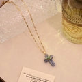 Dettaglio del ciondolo a croce dorata con trama in pietra blu e cuore di strass verdi - Stile Cuore in Pietra a Puntini Blu (1# Blue Spot)
