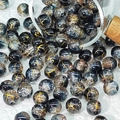 Macro detail of 10mm frosted glass beads with gold wire and foil patterns spilling from a jar - Black & Gold