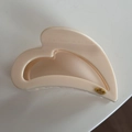Close-up of beige hair claw clip featuring a small golden oval label with Love engraving - Heart-Shaped / Creamy White