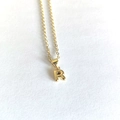 Close-up of minimalist gold initial R pendant necklace on white textured background - Letter R