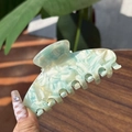 Mint green and white marble acetate hair claw clip held by hand in a natural setting - Green Floral Colorful - 7 Teeth Claw