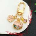 Detail view of pink enamel flower and shell charms on a gold U-shaped keychain - Enamel Pink Shell Cherry Blossom Keychain-ER1273
