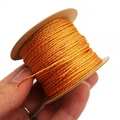 Detailed view of orange and gold 1mm braided thread roll held by hand for size scale - Orange Red