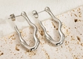 Close-up of silver wavy lava-style earrings on a textured stone display stand - Silver Wave Lava Texture