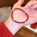 Detailansicht eines roten Achat-Perlenarmbands mit einer türkisfarbenen Akzentperle in der Hand. - Blau-Grüne Perle Achat Stil (16#)