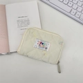 Close-up of quilted cream wallet with cartoon patch and zipper on desk setting - Multicolor Bowknot