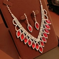Dettaglio del set collana e orecchini con gocce rosse su espositore in velluto marrone - Set di 2 Pezzi Collana + Orecchini / Oro-Rosso