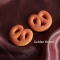 Macro detail of burnt yellow resin pretzel charms on brown satin fabric background - Large / Caramel