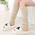 Beige cable-knit leg warmers paired with white plush cross slippers for cozy winter style - One Size / Beige