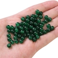 Hand holding green glass jelly jade round beads for DIY handmade jewelry and necklaces - Deep Green approx 50pcs/pack